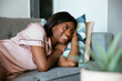 © David Prado/Stocksy - black woman lying on sofa happy