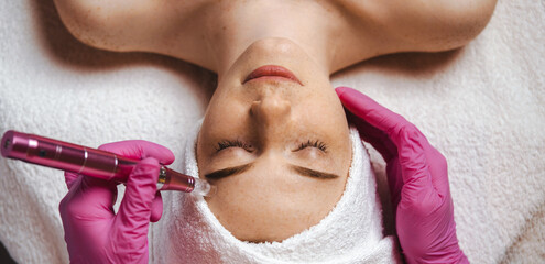 Wall Mural - the cosmetologist's hands making the procedure microdermabrasion of the woman's face. health care, b