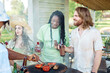© Seventyfour - Cheerful group of friends grilling meat and vegetables while enjoying barbeque party outdoors in Summer