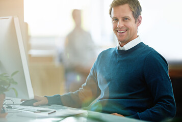 Poster - Portrait of a happy, excited and smiling businessman working on computer at work. Cheerful executive professional with a smile sitting at desktop in modern casual office with colleague in the back.