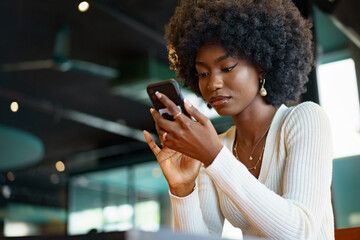 Young afro woman using mobile phone at coffee shop