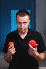 Wall Mural - Portrait of a smiling young man holding stress balls, massage therapist