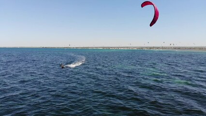 Wall Mural - Kitesurfing from a bird's eye view. Aerial view caucasian slim young woman sportswoman on kitesurfing and kiteboarding in the open sea