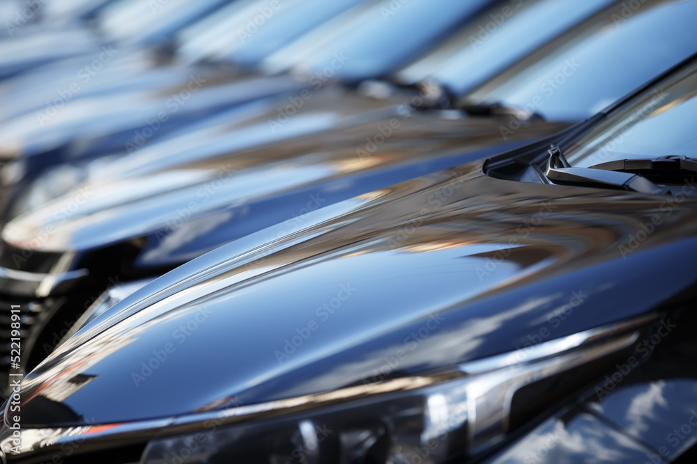The hood of the car. Row of cars on a parking lot. Black sedan cars standing in a row.  Fleet of generic modern cars. Transportation. Many similar new modern shiny cars