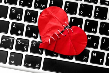 Red heart paper on keyboard computer background. Online internet romance scam or swindler in website application dating concept. Love is bait or victim.