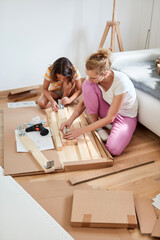 Wall Mural - Mother and daughter assembling new furniture - moving in into a new home.