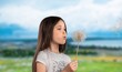 cute little girl blowing dandelions in a sunny flower meadow. Summer seasonal outdoor activities for children.