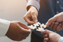 Business People Team Holds In Hand A Jigsaw Or Puzzle Pieces  In The Office For Concept Of Troubleshooting, Teamwork, Unity And Partnership. Success And Strategy Concept.