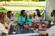© Seventyfour - Diverse group of friends playing Guess who game while sitting at table outdoors in Summer