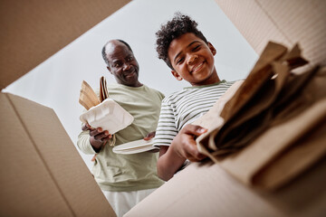 Low angle view of dad teaching his son to separate the garbage, they throwing paper in separate box