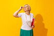 Studio shot of fashionable senior woman in summer style outfit isolated on bright yellow background. Concept of beauty, emotions, vacation, travel