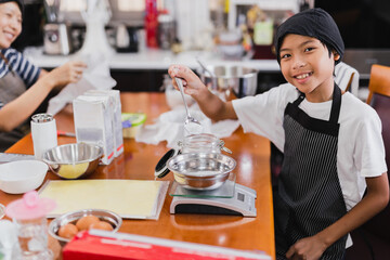 Wall Mural - Young boy and his mum preparing ingredient for baking cake in kitchen.