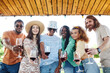 © Seventyfour - Waist up portrait of diverse group of friends looking at camera and holding wine glasses while enjoying outdoor party in Summer