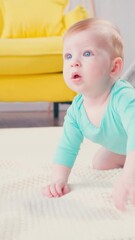 vertical view of baby boy crawling on blanket near yellow sofa