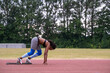 © Cultura Creative - Female runner in starting position on running track