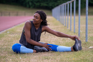 Athletic woman stretching leg on running track