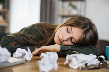 Young frustrated exhausted woman laid her head down on the table sitting at desk with pc laptop. Achievement business career concept. Overworked and tired businesswoman sleeping at work in her office.