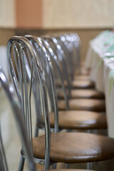 Vertical photo of a chair standing in front of a festive table with food, and other chairs in the background out of focus