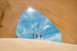 © romylee - Family jumping with joy in front of the entrance of a sand cave
