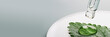 © colnihko - Pipette with Gel cosmetic drop on green leaf in petri dish on grey banner