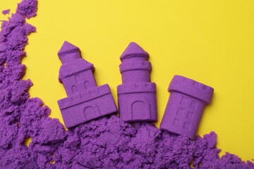 Poster - Castles made of kinetic sand on yellow background, flat lay