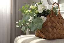 Stylish Wicker Basket With Bouquet Of Flowers On Ottoman In Room