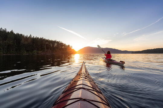 adventurous woman on sea kayak paddling in the pacific ocean. sunny summer sunset. taken near victor