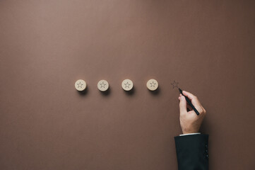 Wall Mural - four stars drawn on wooden cut circles with a hand of a businessman drawing the fifth one