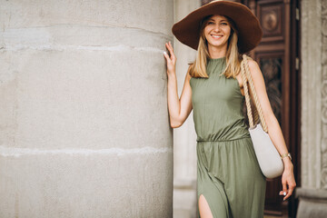 Beautiful woman in dress and hat standing by architecture