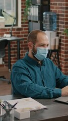 Poster - portrait of business man with face mask working with laptop in startup office. employee using comput
