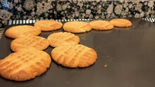 Delicious Shortbread Cookies Of Orange Color Lie On A Brown Baking Sheet Black Take One Cookie With A Spatula And Take It Out Of It Crumbly And Appetizing Cookies, It Is Still Warm. High Quality 4k