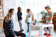 © Татьяна Волкова - Group of adorable children pupils studying colorful numbers hung on wall with help of young teacher in classroom. Craft.
