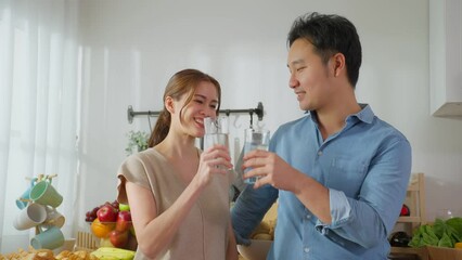 Wall Mural - Asian attractive couple drinking a glass of water in kitchen at home. 