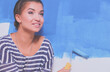 © lenets_tan - Happy beautiful young woman doing wall painting, standing near ladder