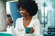 © fotofabrika - Portrait of a beautiful young african woman using her cellphone in a cafe