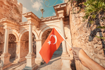 Wall Mural - Turkish Flag in hand and famous gate or Hadrian arch in Antalya. Travel landmarks and must-visit tourist and sightseeing sites in Turkey