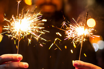 Two sparklers in your hands on a blurred background outside at night. Concept: Merry Christmas. New Year holidays and weekends. Time with family. December 25