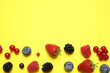 Leinwandbild Motiv Mix of fresh berries on yellow background, flat lay. Space for text