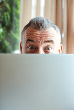 Closeup Photo Of Cheerful Mature Businessman Working With Laptop Computer And Peeking Out From Behind Monitor, Free Copy Space. Remote Job, Working Time, Freelance, Busy People, Having Fun