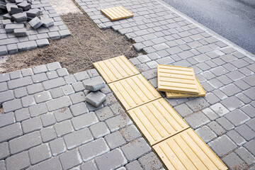 Laying tactile tiles for visually impaired. Horizontal guide strips for blind handicap on tiles pathway, walkway for blindness people.