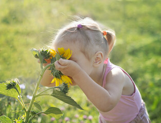 Canvas Print - little girl sniffing a sunflower.