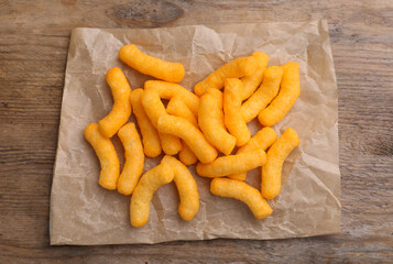 Wall Mural - Many tasty cheesy corn puffs on wooden table, top view