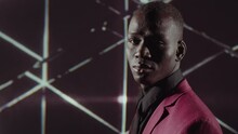 Portrait Of African American Man Wearing Magenta Jacket With Black Shirt And Tie Turning His Face To Camera, Kaleidoscopic Pattern Animation On Background