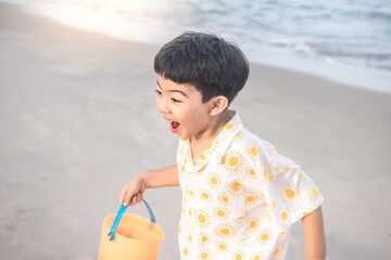 Cute boy running on the beach. He holds a plastic toy and running happily and happy time.