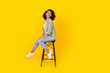 © deagreez - Full length profile photo of brunette lady sit on chair look up wear shirt jeans boots isolated on yellow background