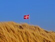 © RooM The Agency - Danish flag blowing in the wind over the top of a sand dune, Fanoe, Jutland, Denmark