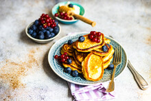 Close-up Of A Plate Of Pancakes With Fresh Blueberries, Redcurrants,  Cream And Honey