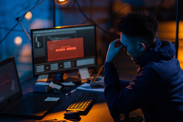 Poster - cybercrime, hacking and technology concept - male hacker in dark room writing to notebook and using computer virus program for cyber attack