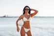 © Syda Productions - people, summer and leisure concept - happy smiling young woman in bikini swimsuit posing with volleyball on beach