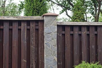 Sticker - part on gray brown wall of a fence made of wooden boards and stones on the street